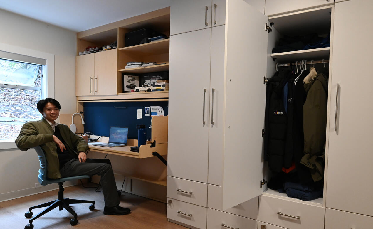 A student sits at a desk next to large storage cabinets