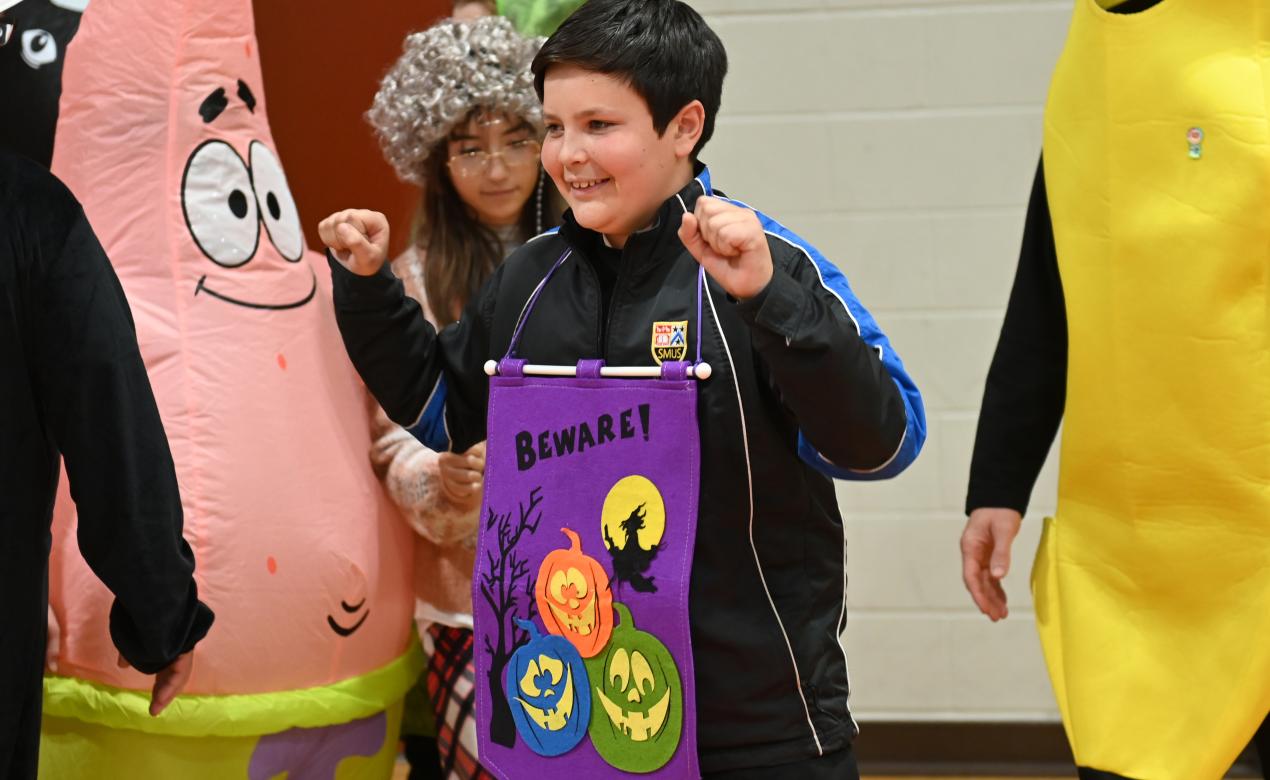 A student wears a purple Halloween banner that reads 'Beware!'