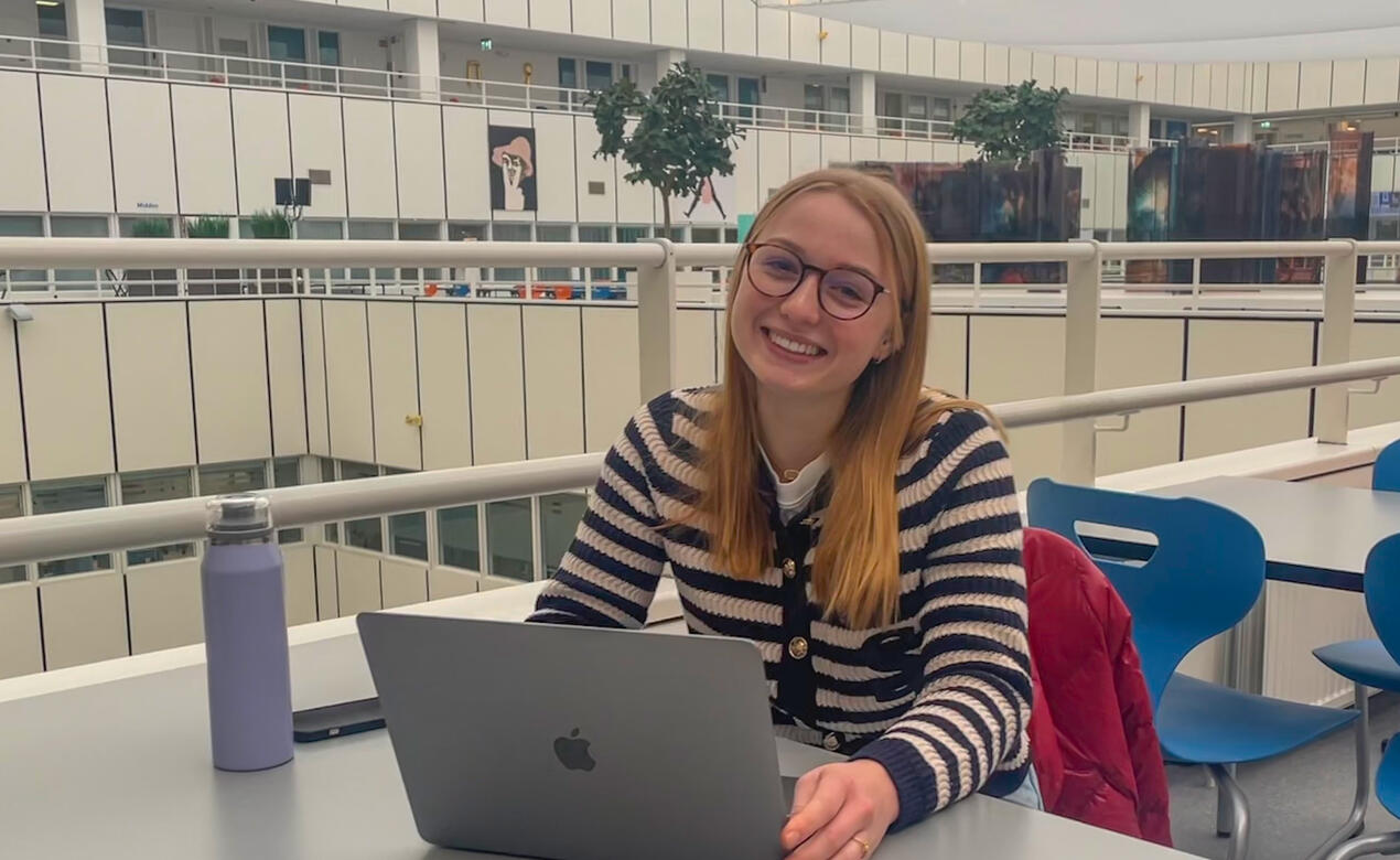 Fay sitting with a laptop in Maastricht University