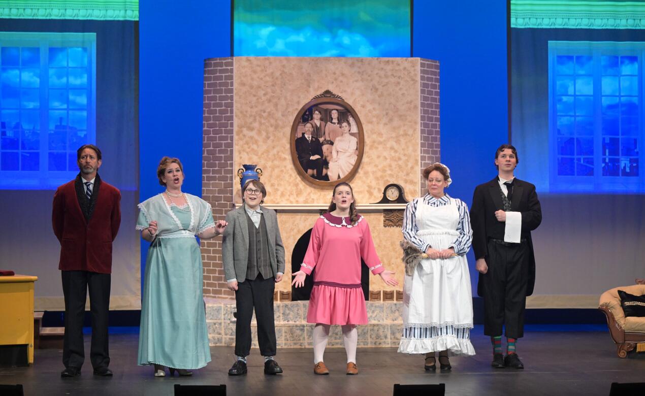Six characters stand in a line singing in the Mary Poppins show on stage