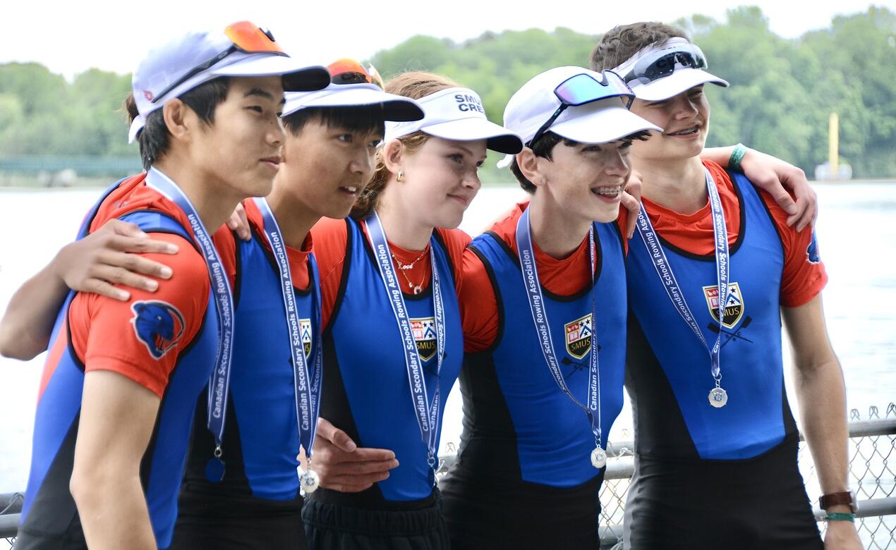 The SMUS coxed four men's crew stand with medals around their neck after winning at Nationals.