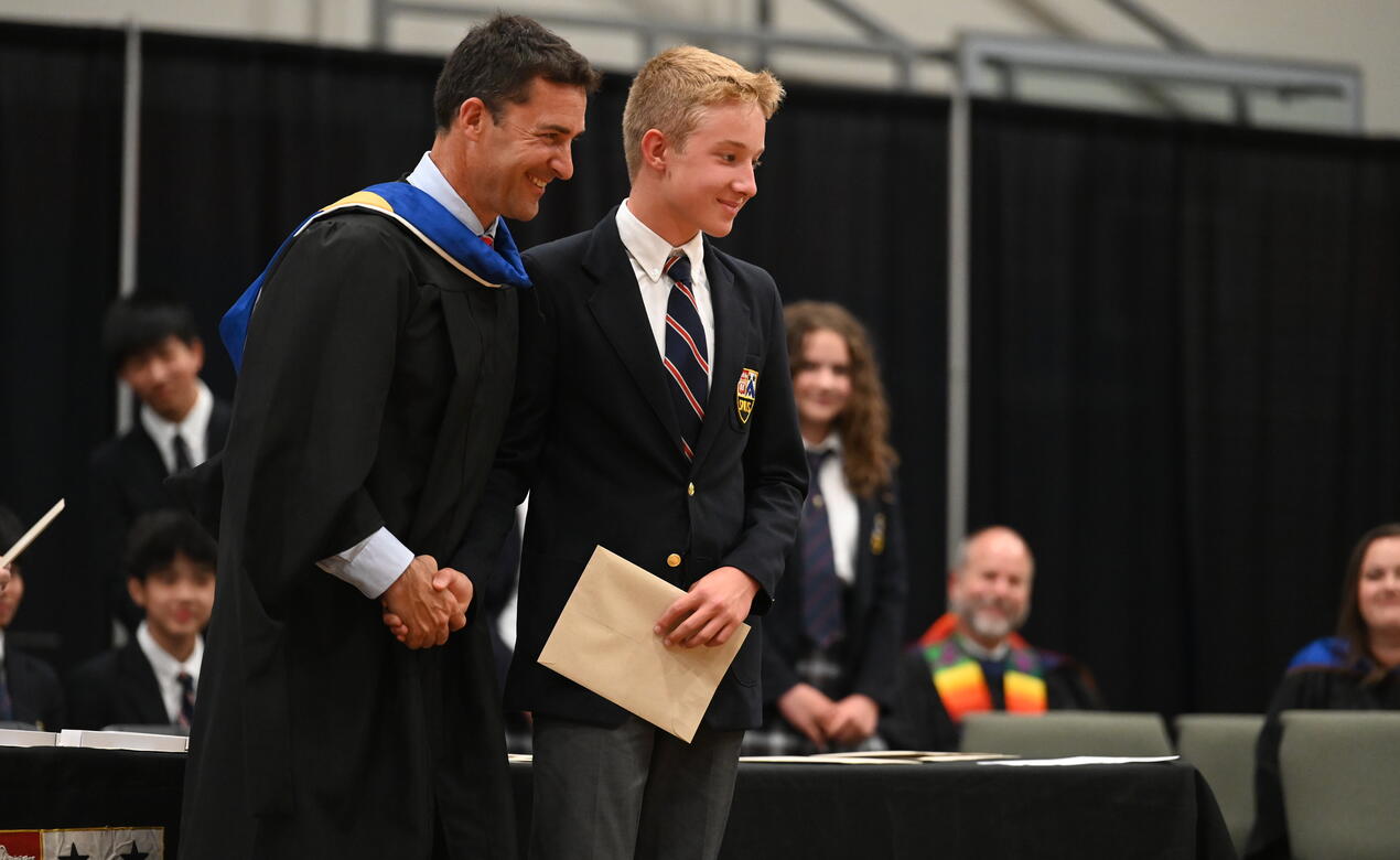 Acting Head of School Eliot Anderson shakes a Grade 8 students' hand at the Middle School Closing Ceremonies.