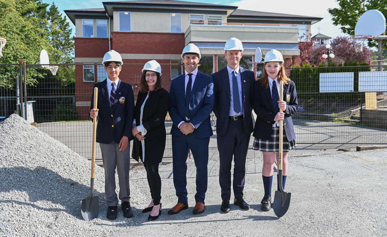 A group of SMUS representatives including two students, Chair of the Board of Governors, Acting Head of School and Director of Middle School stand with hard hands and shovels at the ground breaking for the Middle School Project.