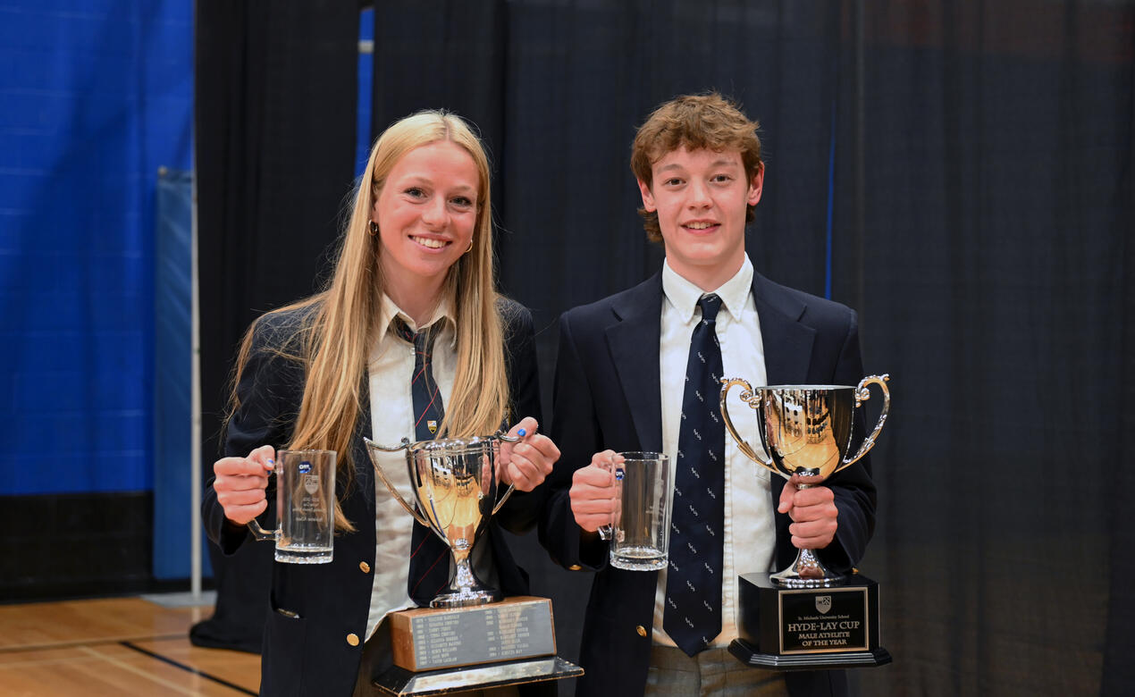 Outstanding Athletes of the Year Maddy Albert and Wil Woods stand beside each other holding their trophies.