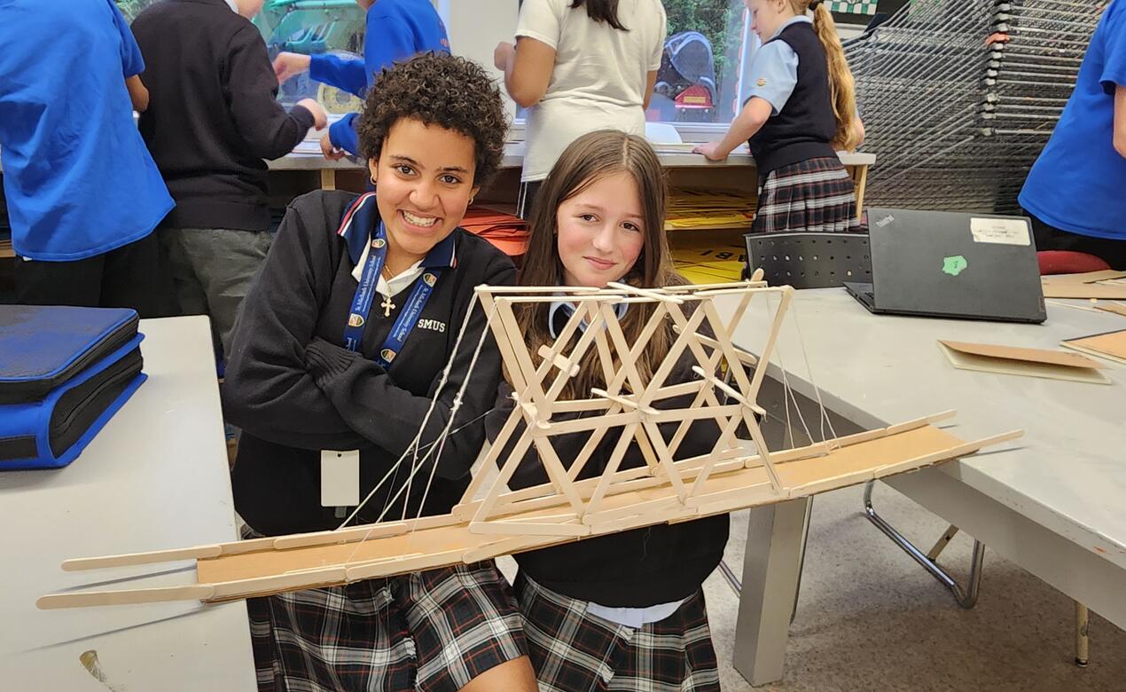 Two students pose with their bridge 