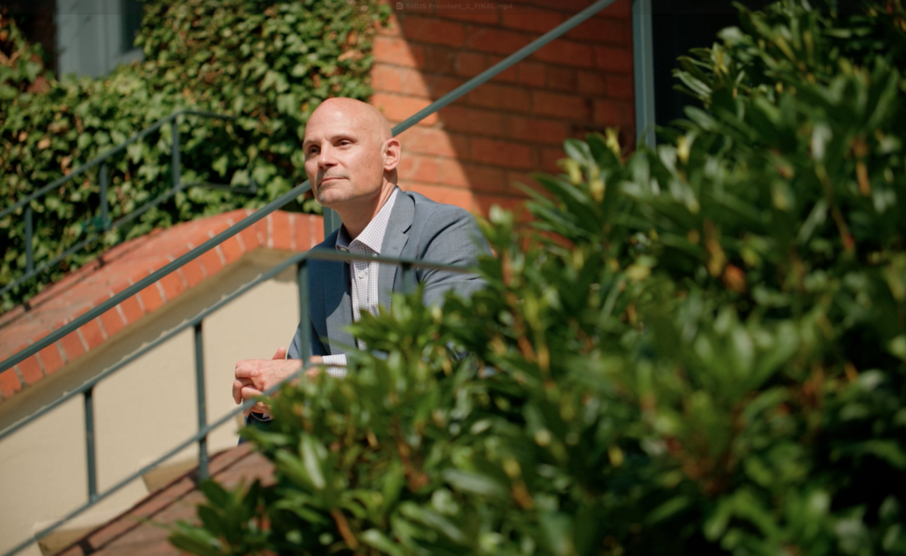 Jeff Aitken sits on the steps of the School House Building looking out