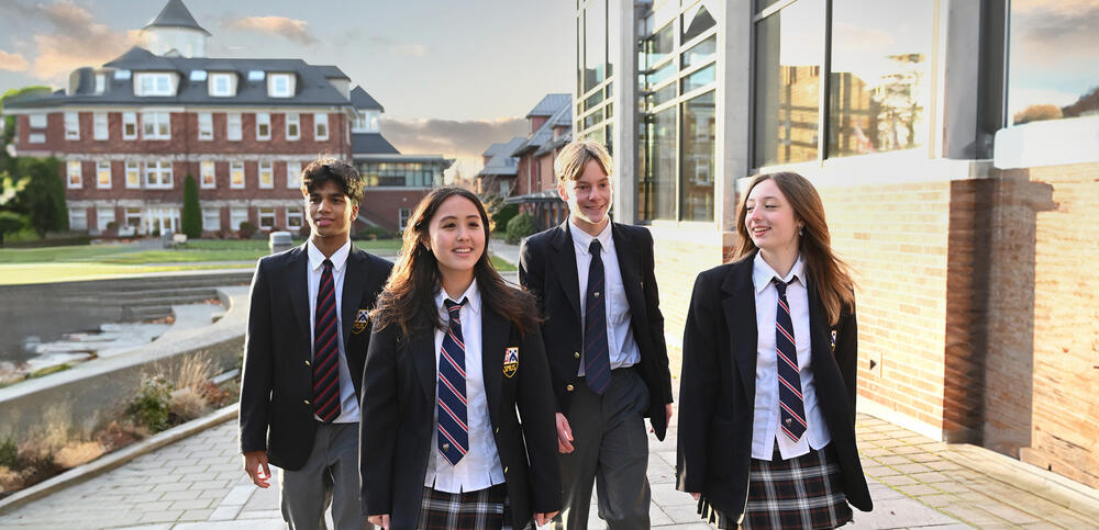 Students dressed in school uniform walk between campus buildings