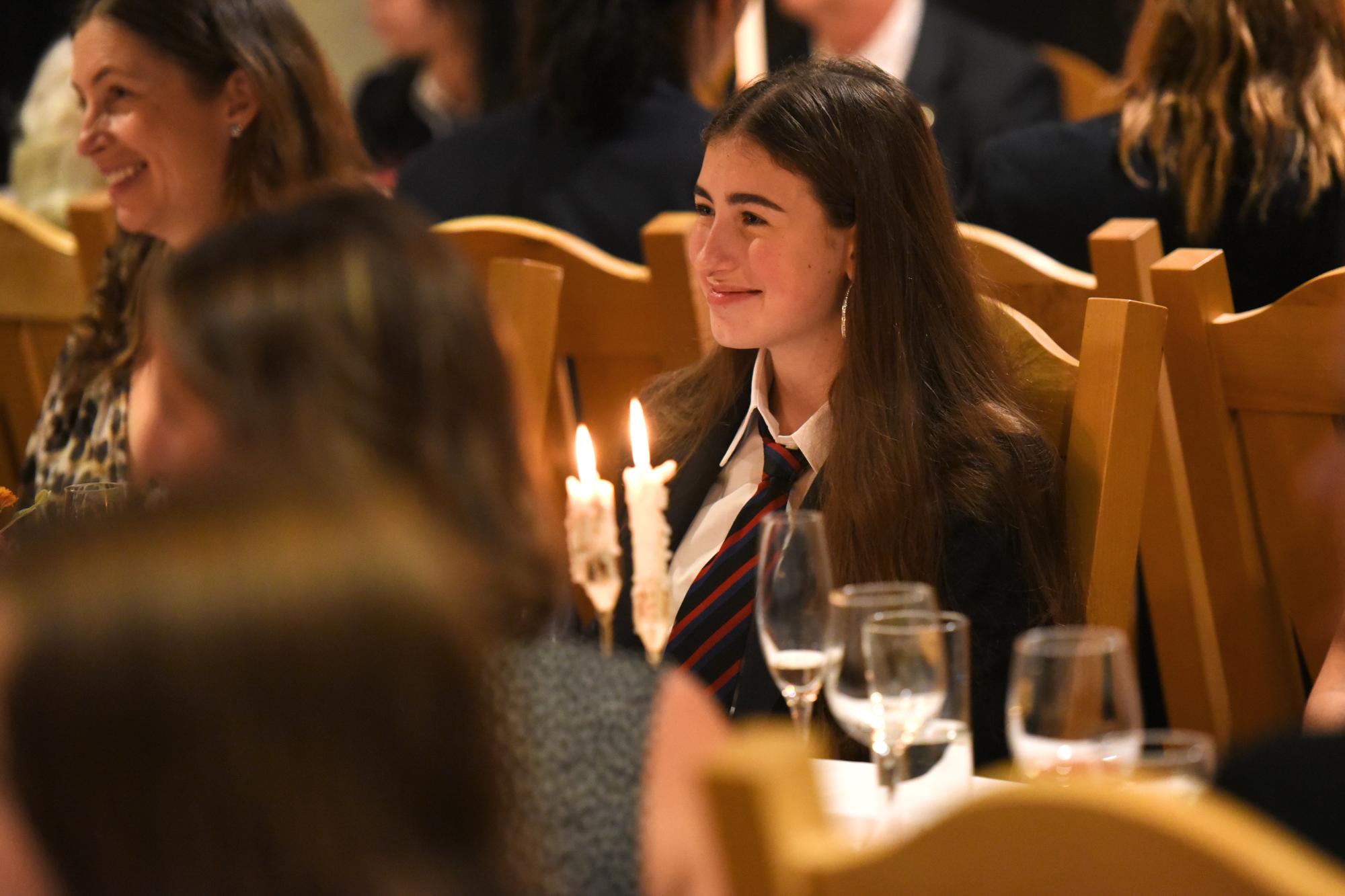 A student sits in the Graves Hall dining hall wearing Number 1 uniform during a beautiful evening ceremony