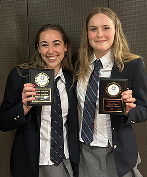 2 students stand with their tournament awards