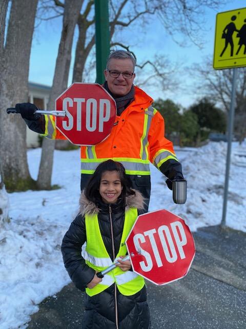 A young Victoria Arneja stands with Mr. Turner during crossing guard duty